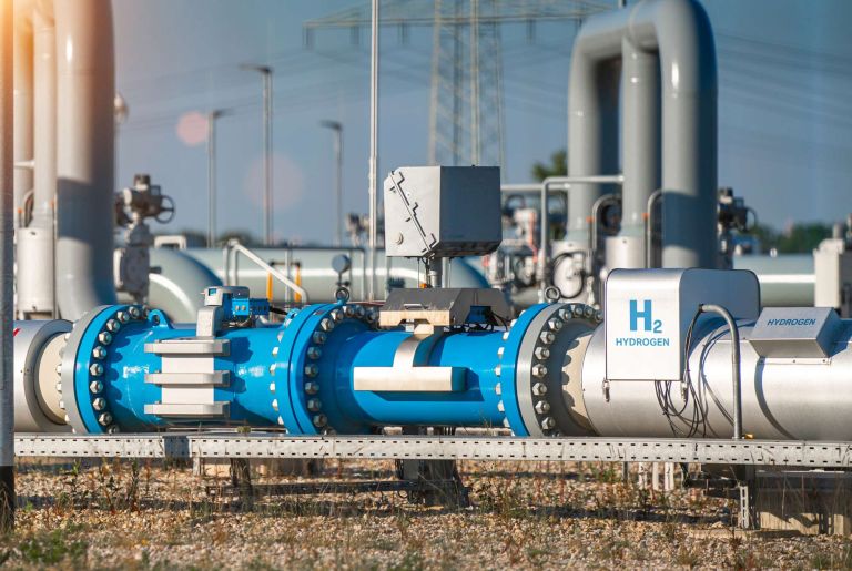 A large blue and white hydrogen pipeline system with powerlines in the background