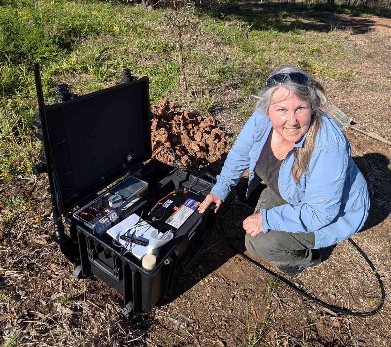 Woman kneeling in front of a small seismometer