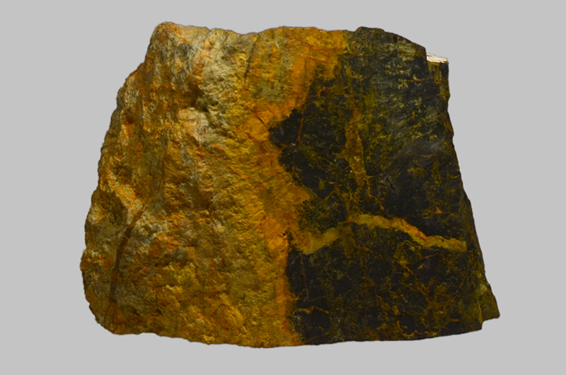 A half bright yellow and half green to grey coloured rock. In the darker section there is a yellow vein.
