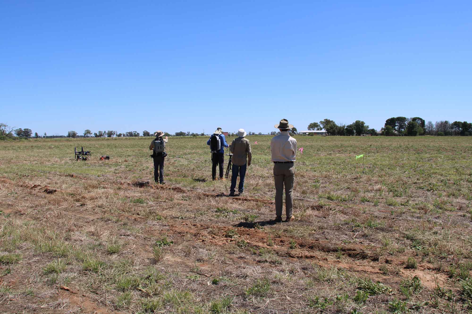 Group of people standing in a field taking measurements