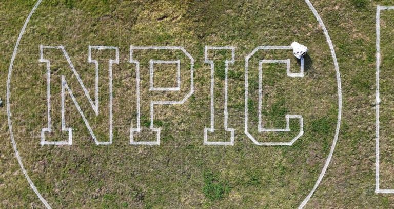 large letters, N P I C, painted on a sports field
